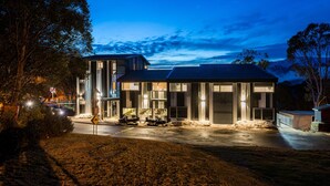 Uma casa moderna de dois andares, com garagem, janelas amplas e entrada por meio de um caminho.
