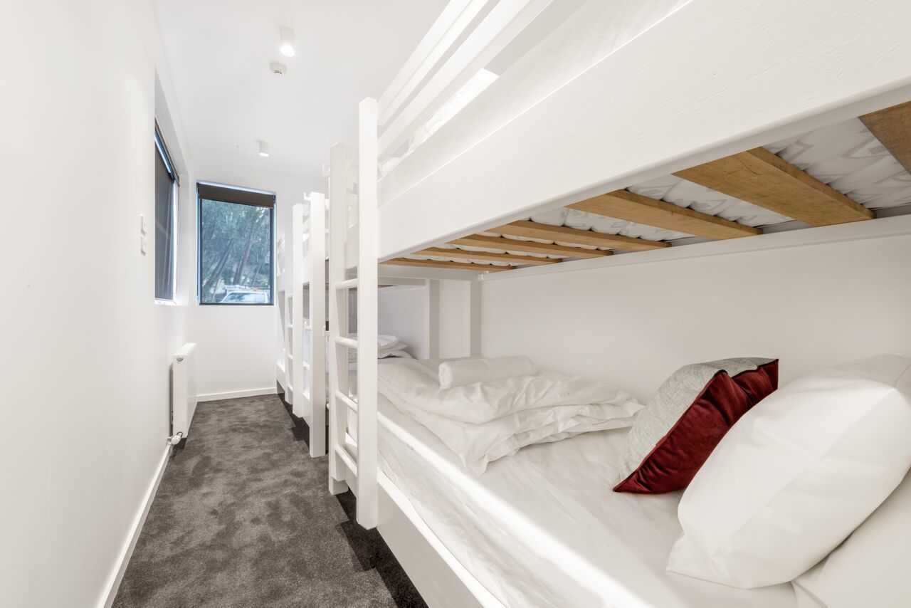 Dormitorio con literas y vistas a árboles a través de una ventana.