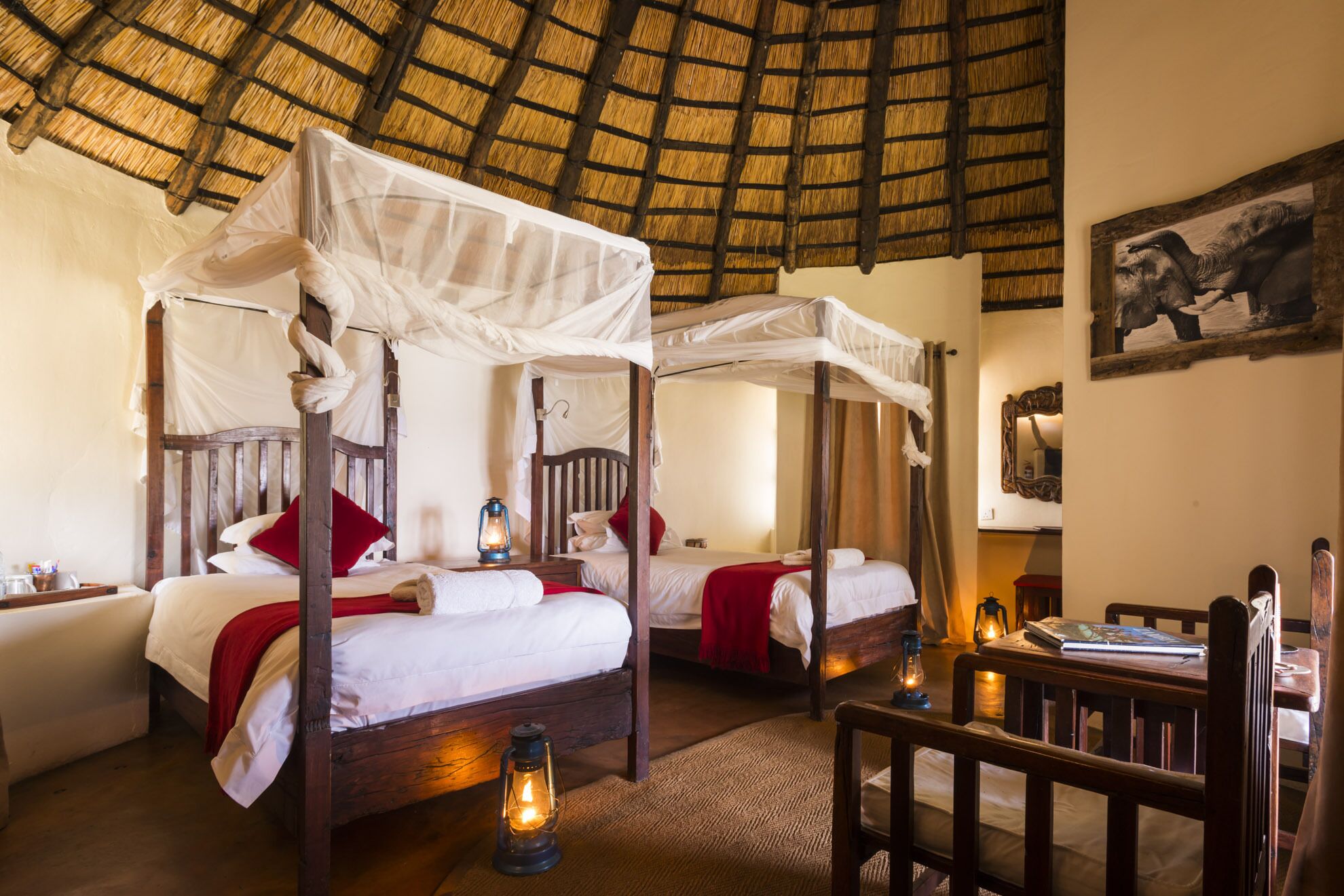A traditional room with four beds, each with a canopy, and a thatched roof.