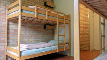 A bunk bed room with a brick wall, a wooden ceiling, and a door leading to another room.