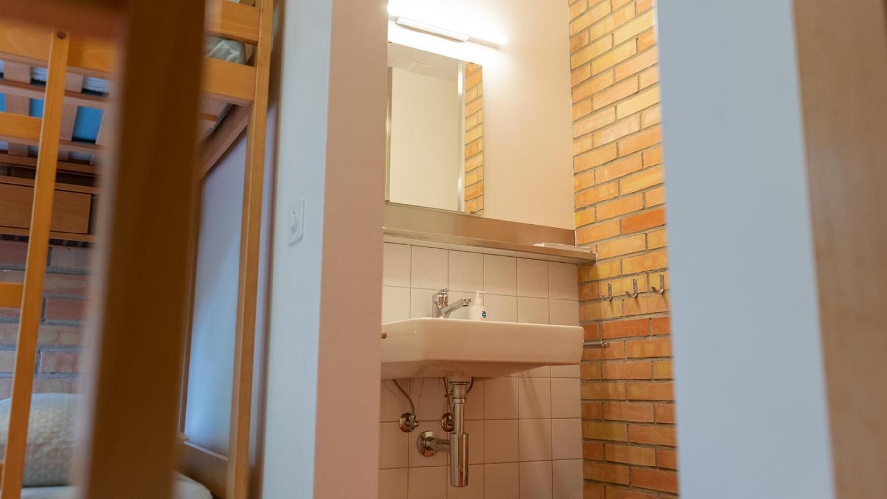 Un baño con pared de azulejos, un lavamanos y un espejo.