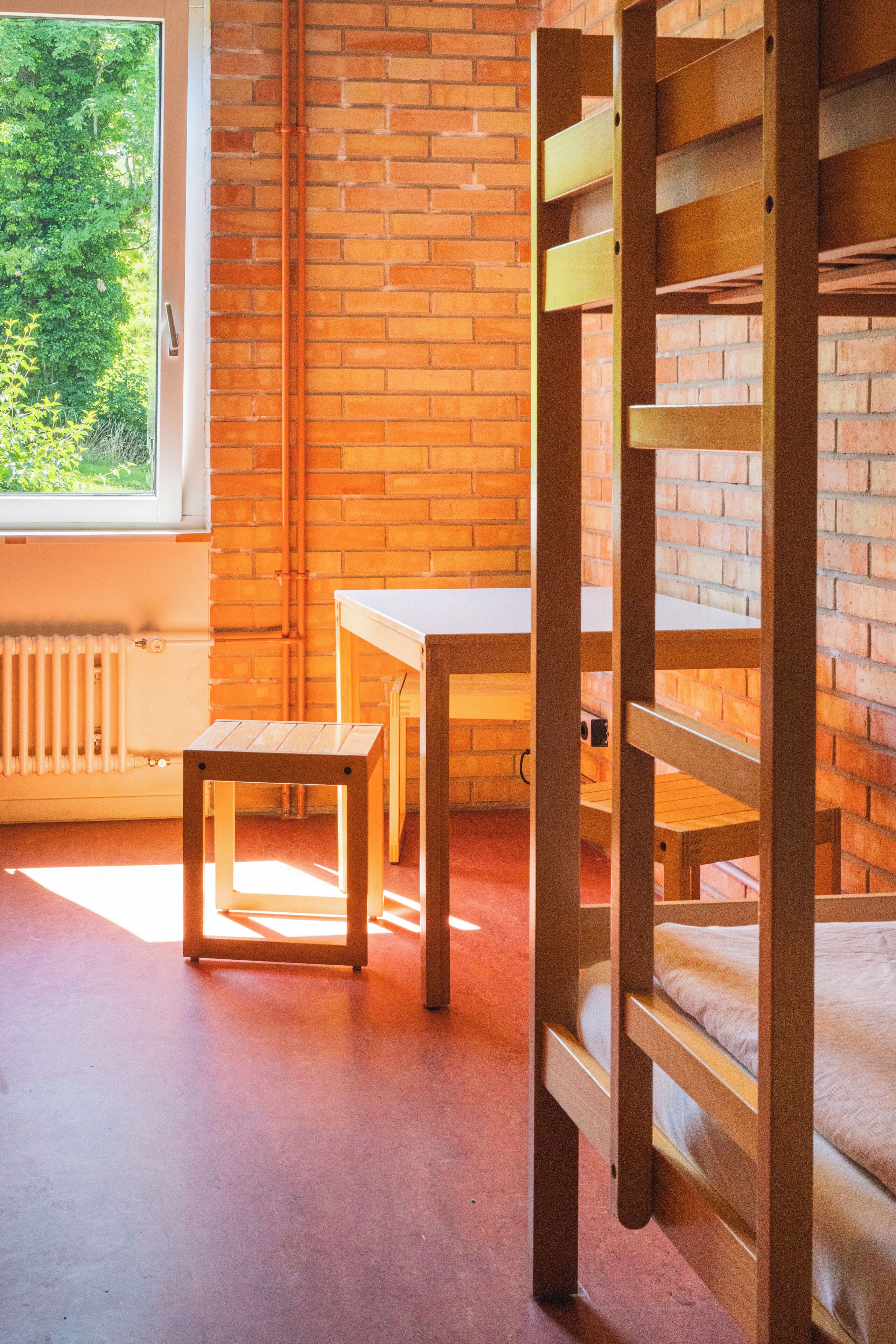 Een kamer met een stapelbed, een klein tafeltje en een radiator.