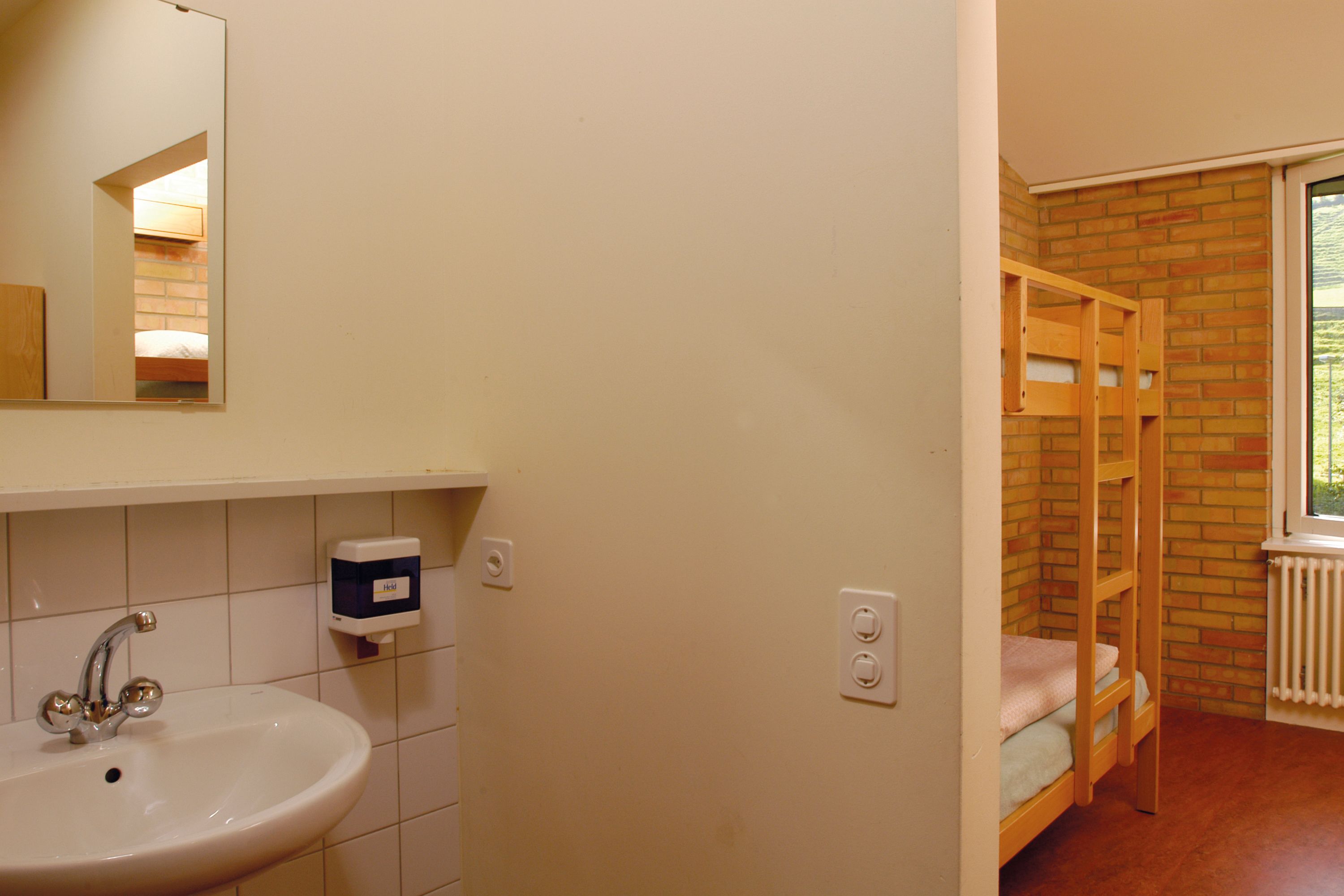 Ein Badezimmer mit Waschbecken, Spiegel und einem Holzbett.