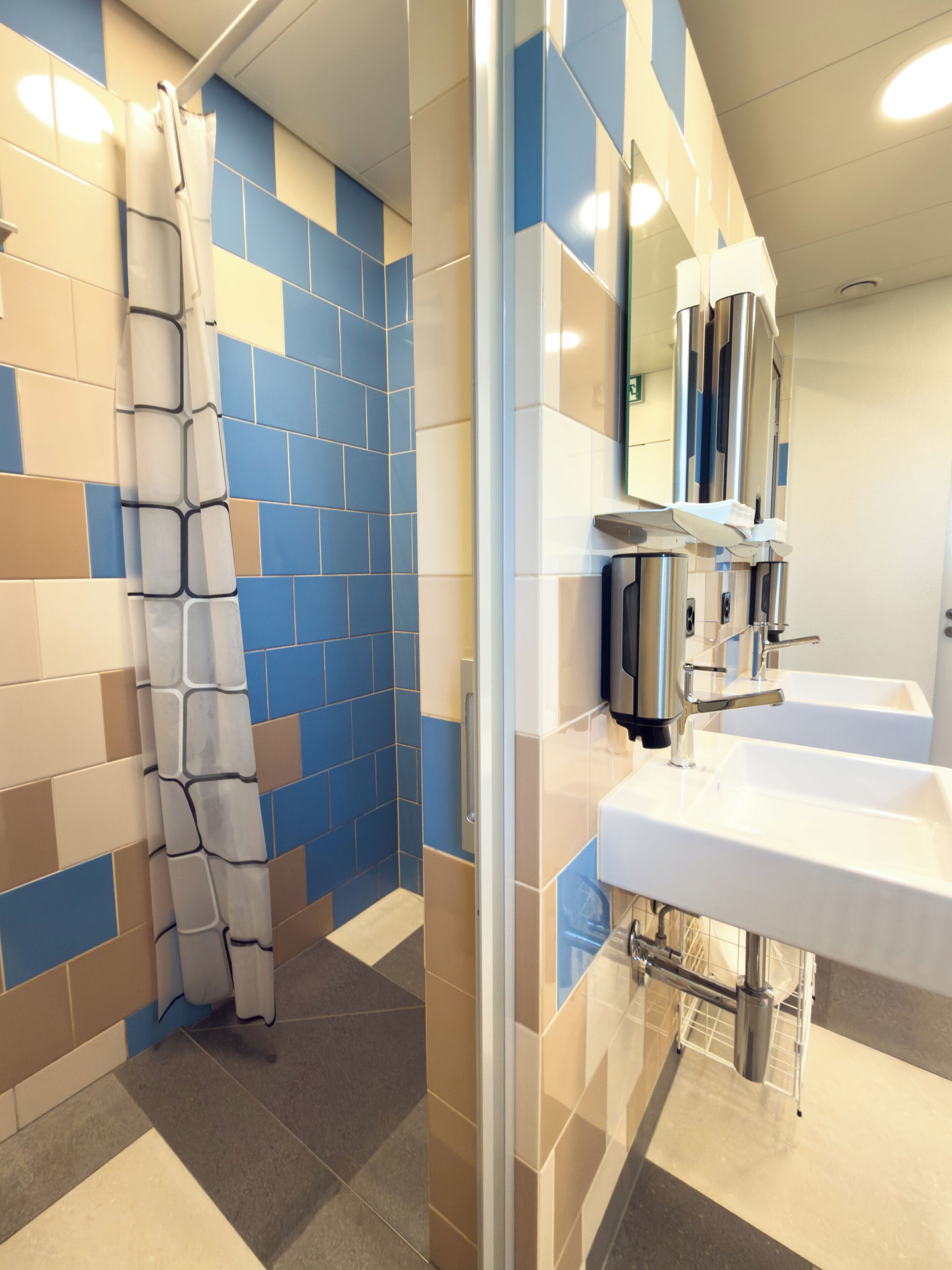 A bathroom with a shower curtain, tiled walls, and a sink with a mirror.