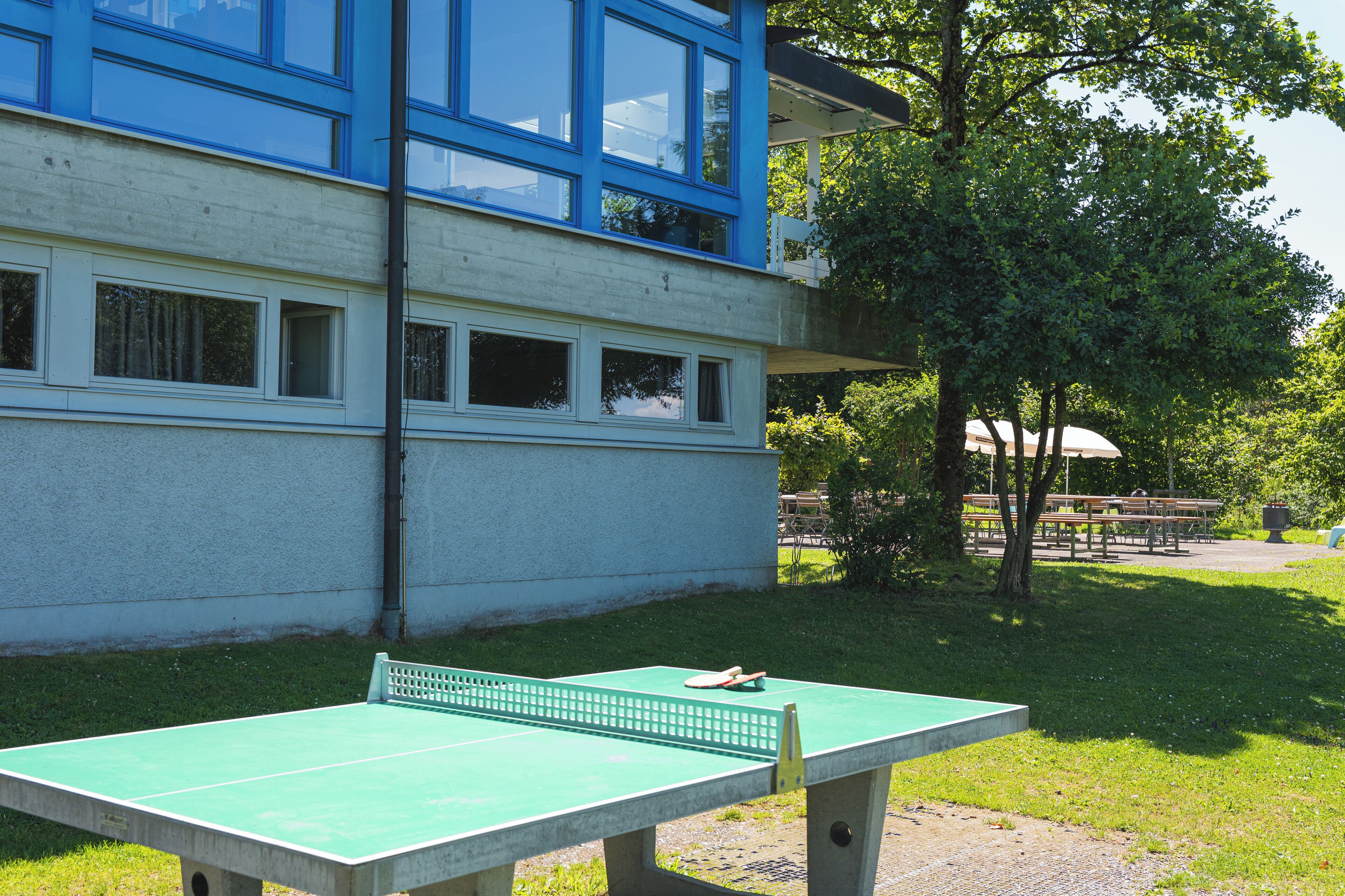 Una mesa de ping pong verde en un espacio exterior, con un edificio al fondo.