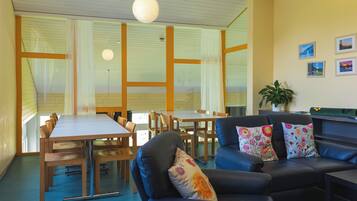 A modern interior with a dining area, a sofa with floral cushions, and a plant on a table.