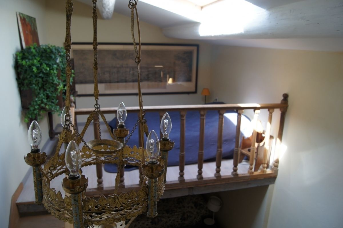 A chandelier in a room with a wooden railing and a blue cushion.