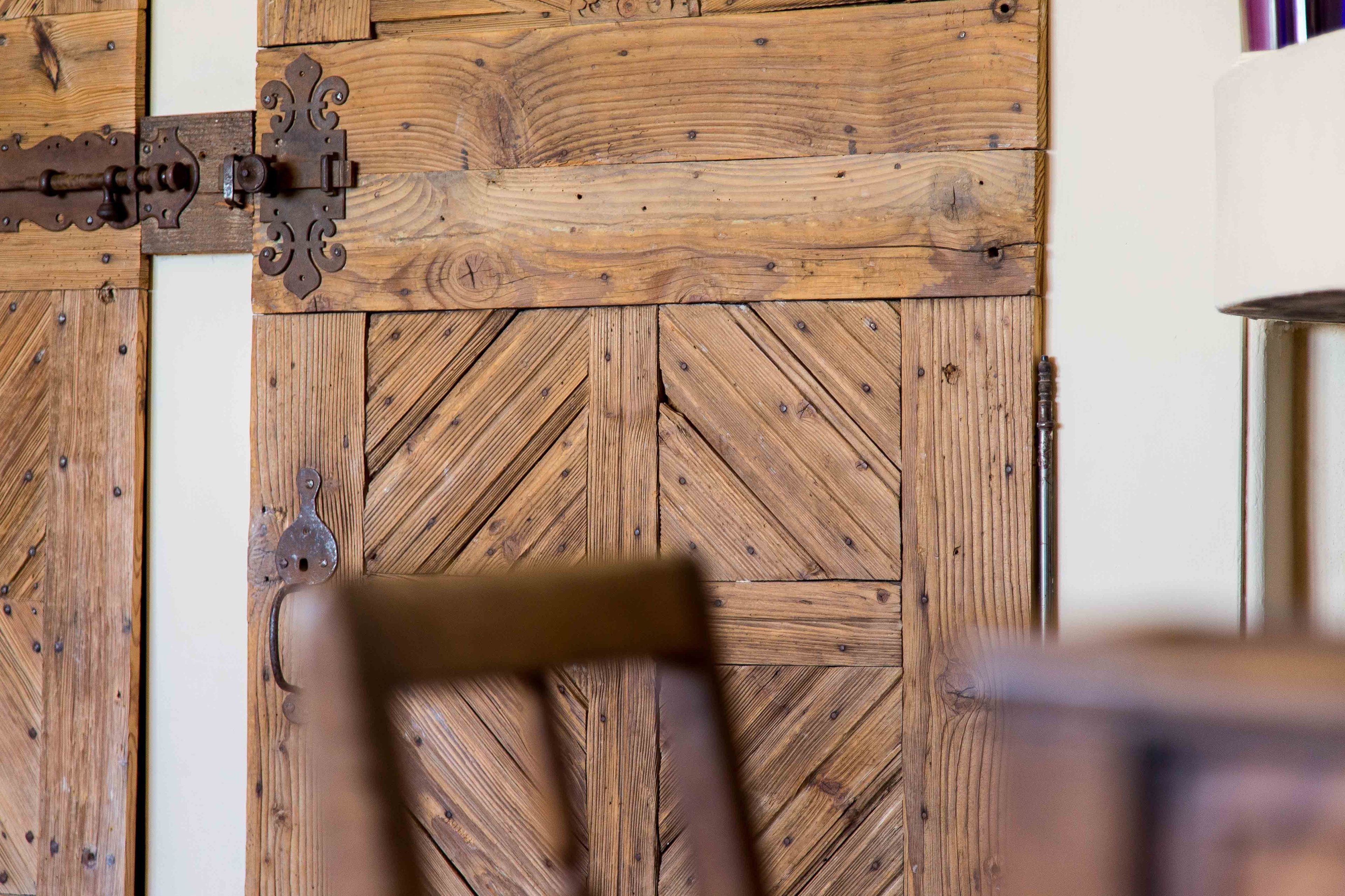 Une porte en bois avec un loquet métallique et un motif en chevrons.