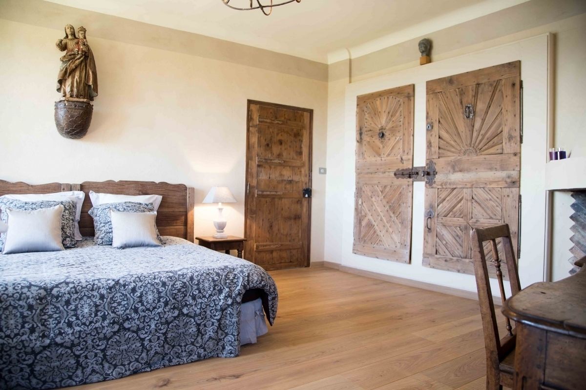 Een slaapkamer met een groot bed, houten deuren en een beeld aan de muur.