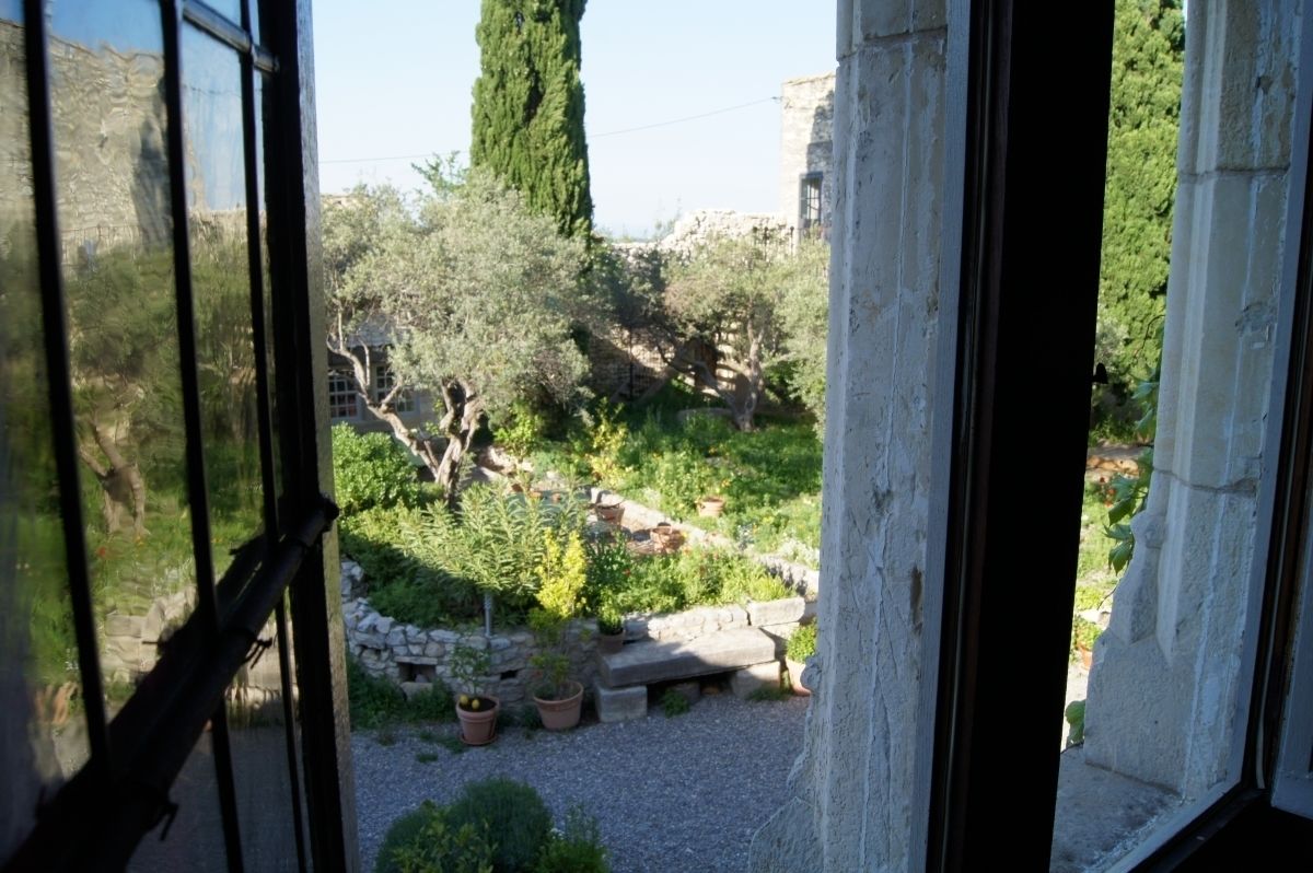Un jardín con senderos de piedra, plantas en macetas y un banco de piedra.