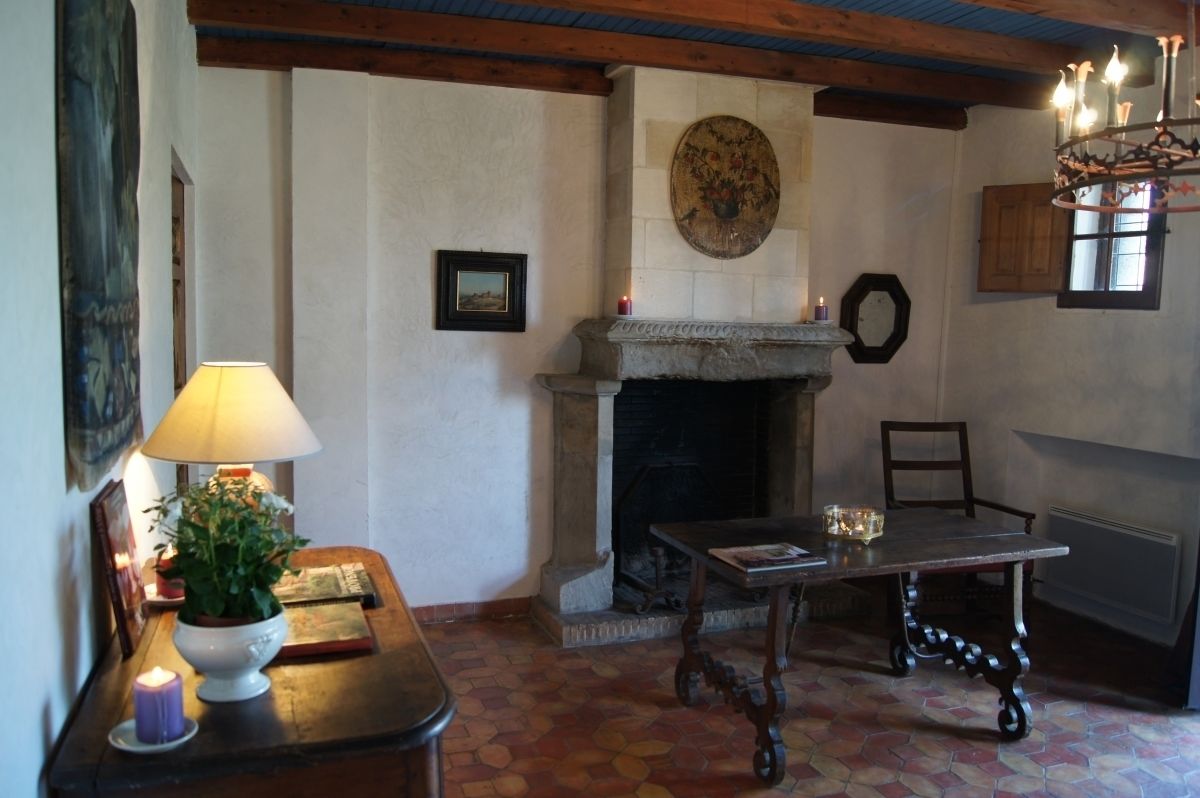 A cozy room with a fireplace, a table, and a lamp.