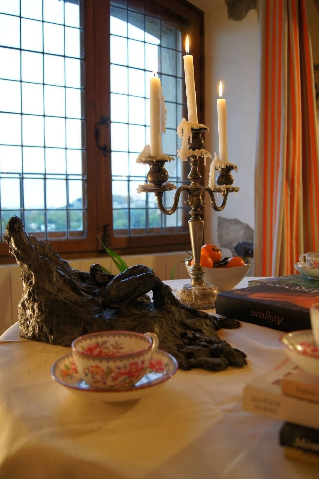 Una taula amb un portaveus de llum, un llibre i una peça decorativa.