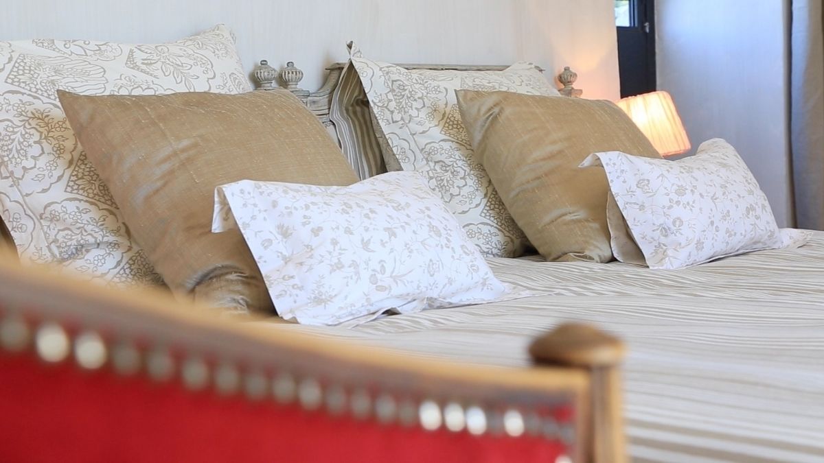 A neatly made bed with patterned pillows and a red headboard.