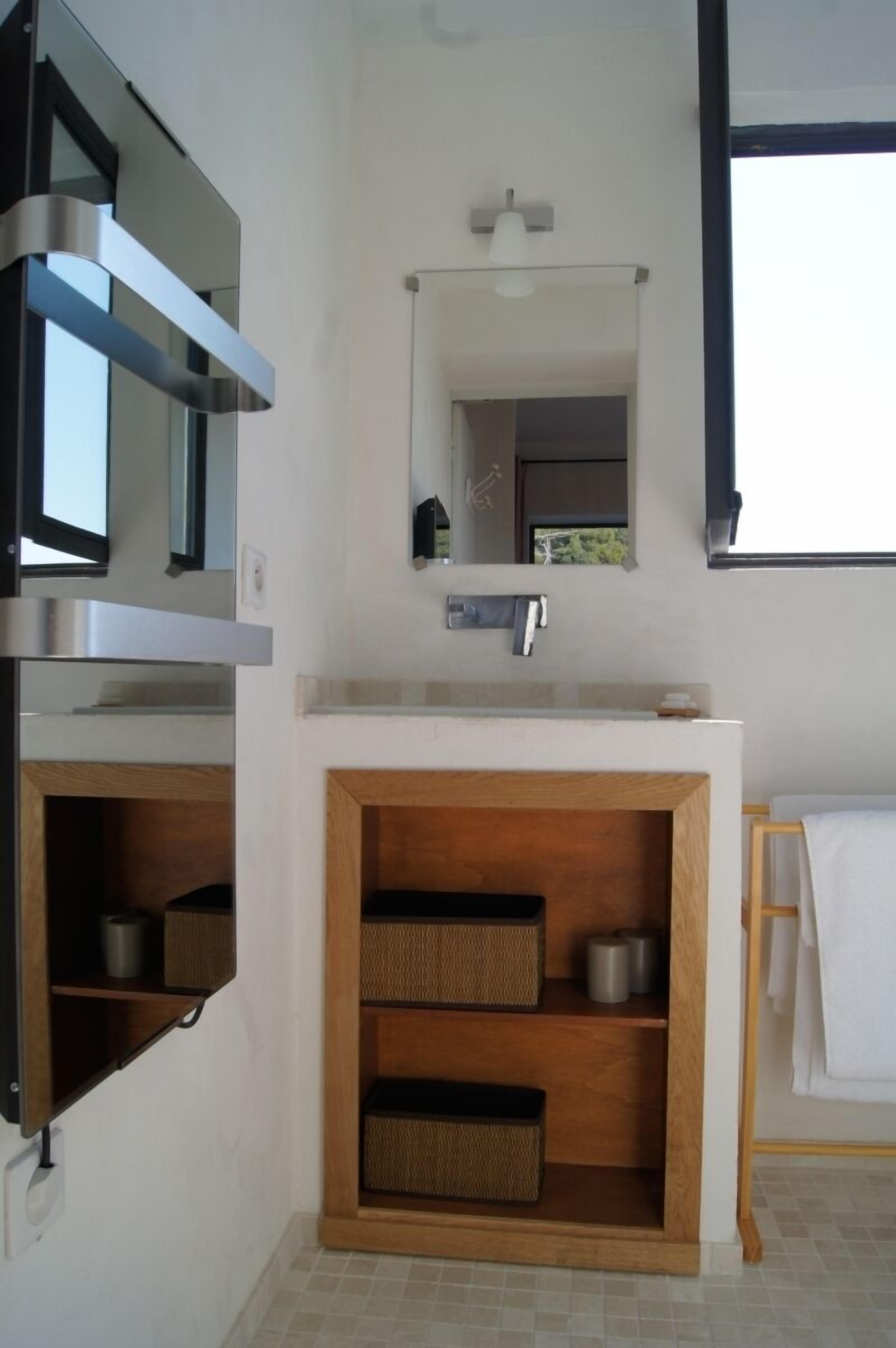 A modern bathroom with a built-in sink, mirror, and wooden storage shelves.