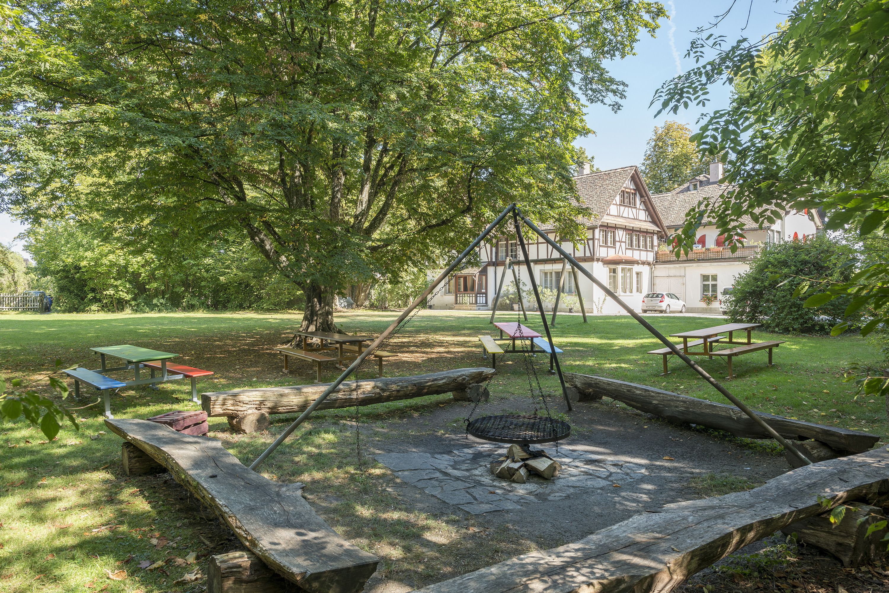 Ein Park mit Picknicktischen, einer Schaukel und einem großen Baum.