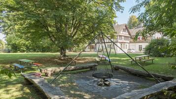 Ein Park mit Picknicktischen, einer Schaukel und einem großen Baum.