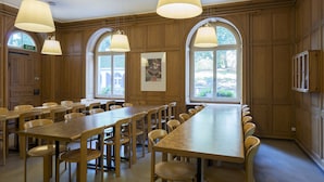 A conference room with long tables and chairs, wooden paneling, and large windows. - Youth Hostel Schaffhausen (Schaffhausen)