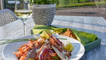 A plate of seafood salad with a glass of white wine and a potted plant on a table.