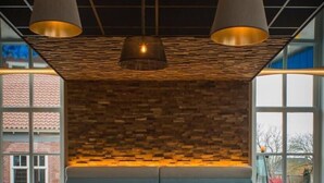 A modern interior with a patterned wall, a bench, and pendant lighting. - Hotel Termunterzijl (Termunterzijl)