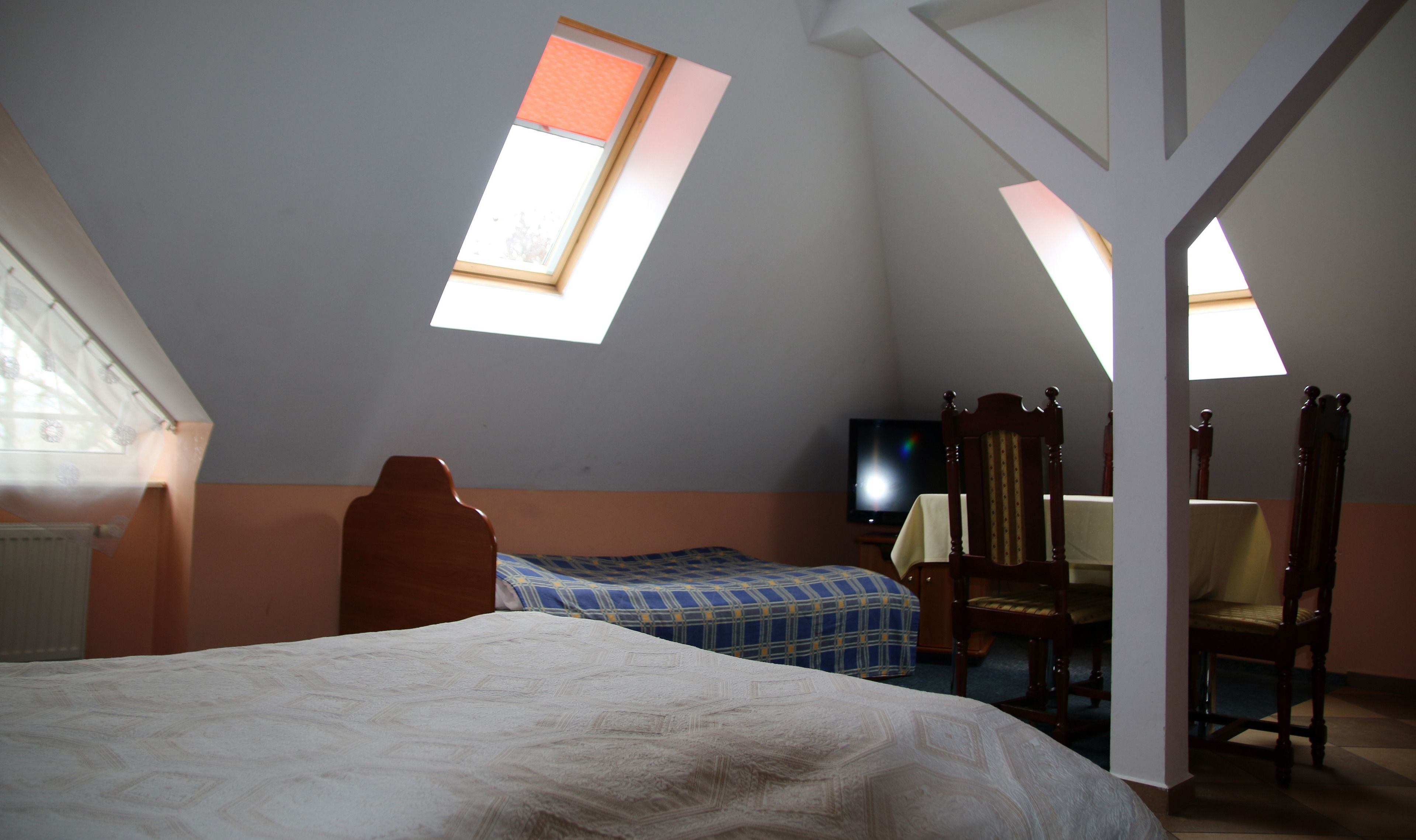A bedroom with a bed, a chair, a television, and a window.