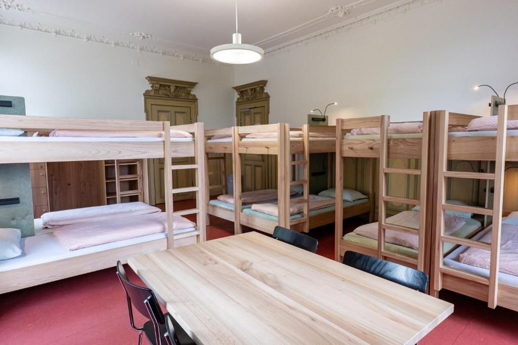 Een kamer met stapelbedden, een houten tafel en een stoel.