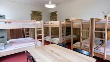 Een kamer met stapelbedden, een houten tafel en een stoel.