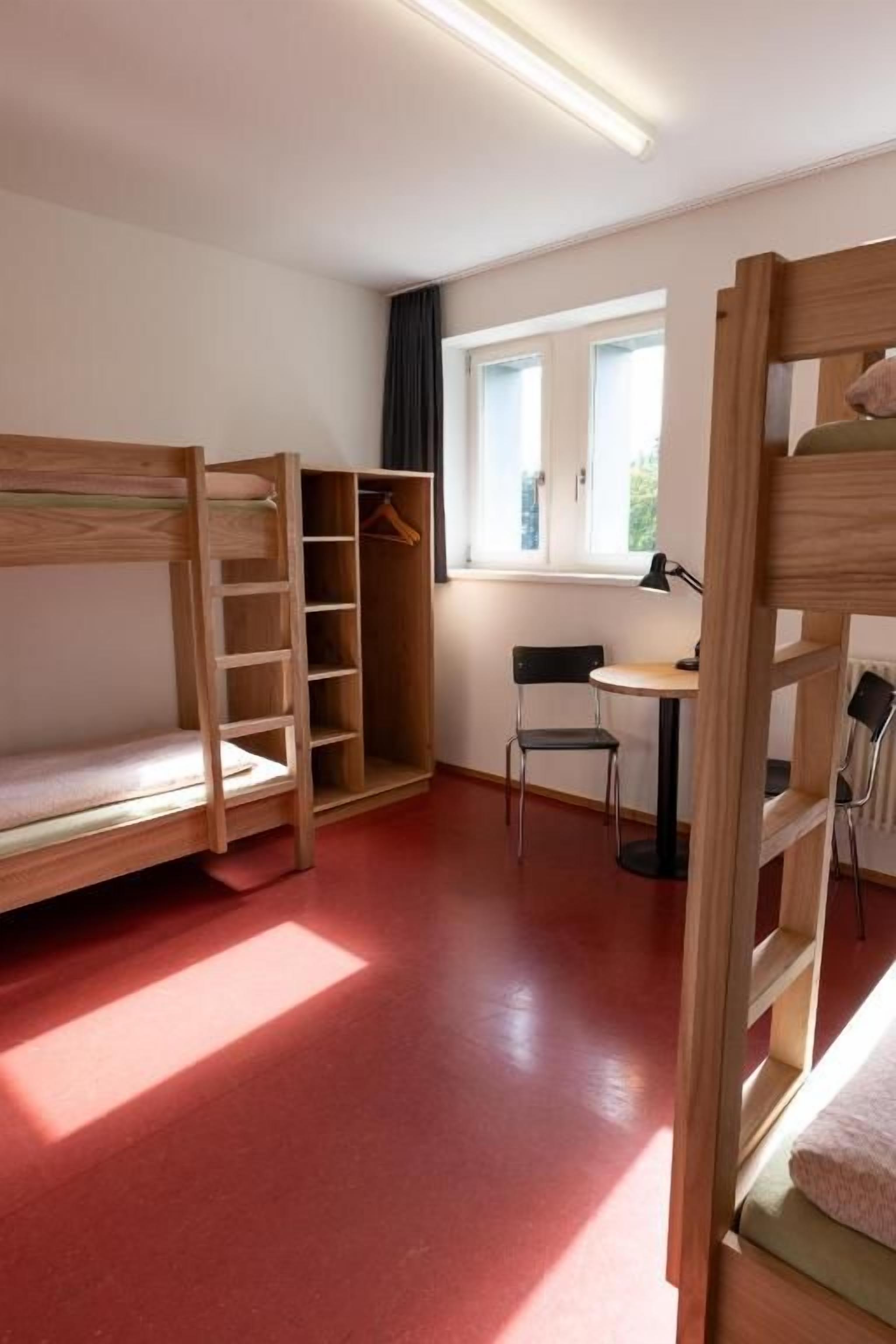 A room with bunk beds, a desk, and a chair.