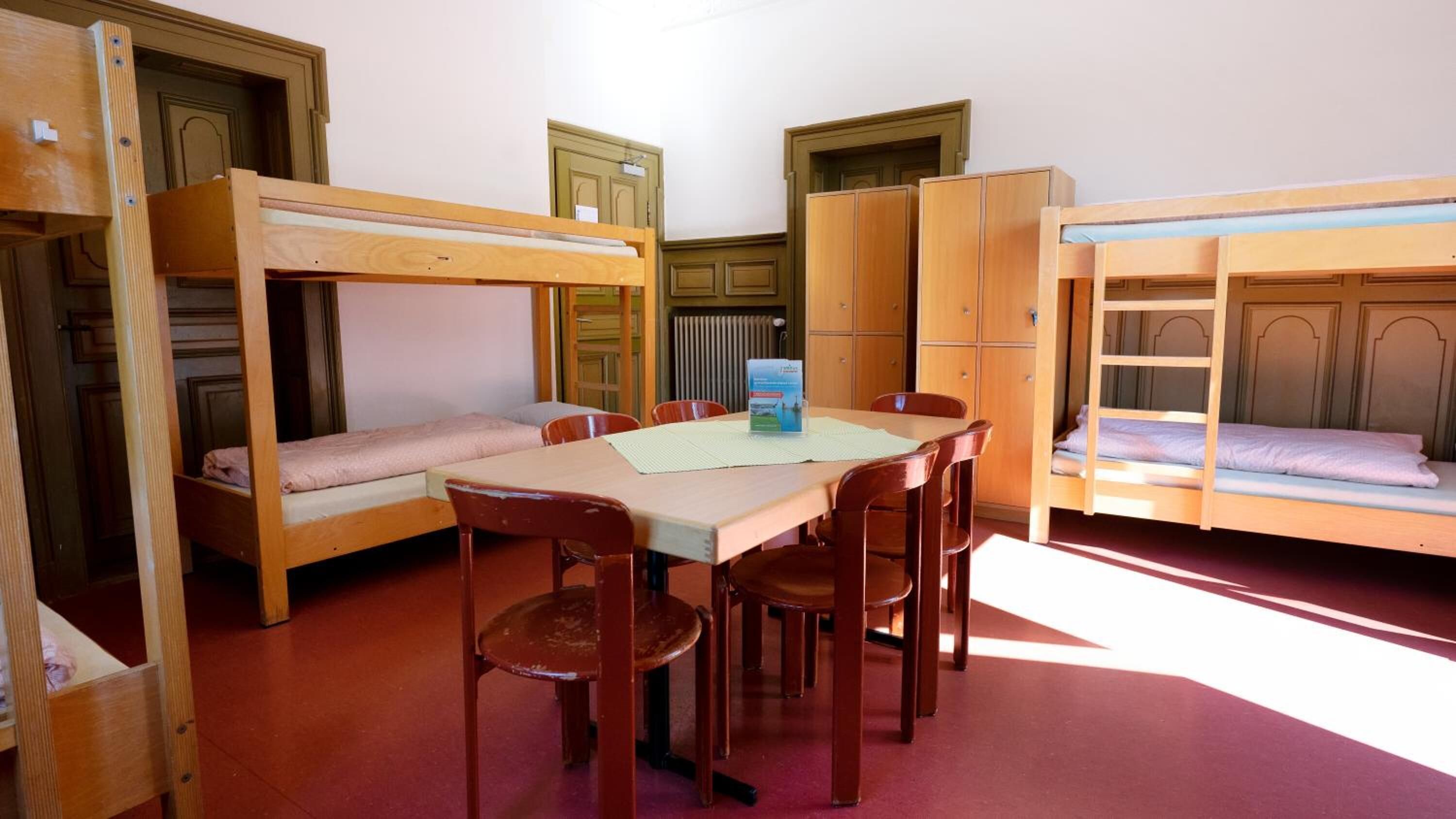 Un dormitorio con literas, una mesa de comedor con sillas y armarios de madera.