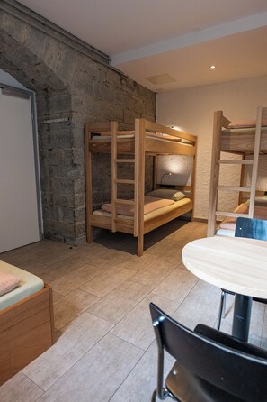 A bunk bed room with a stone wall, a desk, and a chair. - Youth Hostel Kreuzlingen (Kreuzlingen)