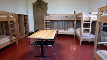 Dormitorio con literas, una mesa de madera y sillas, un armario y una puerta.