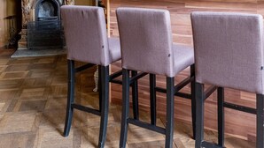 Une pièce avec un plafond en bois, un papier peint à motifs, une cheminée et une table entourée de chaises.