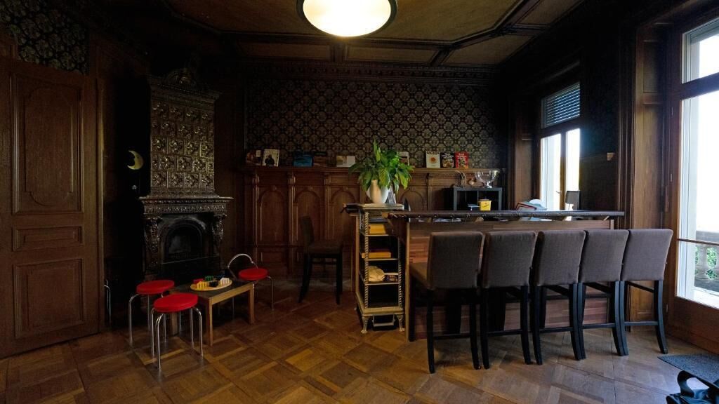 Ein gemütliches Zimmer mit Kamin, einer Holztresorecke und einem großen Fenster, das für natürliches Licht sorgt.
