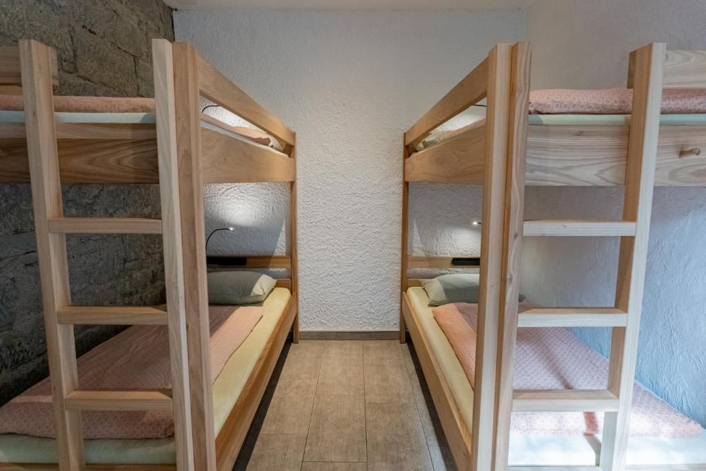 Une pièce avec des lits superposés, des échelles en bois et un mur à texture.