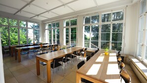 Un vaste espace dédié à la salle à manger, doté de grandes fenêtres, de nombreuses tables et de chaises.