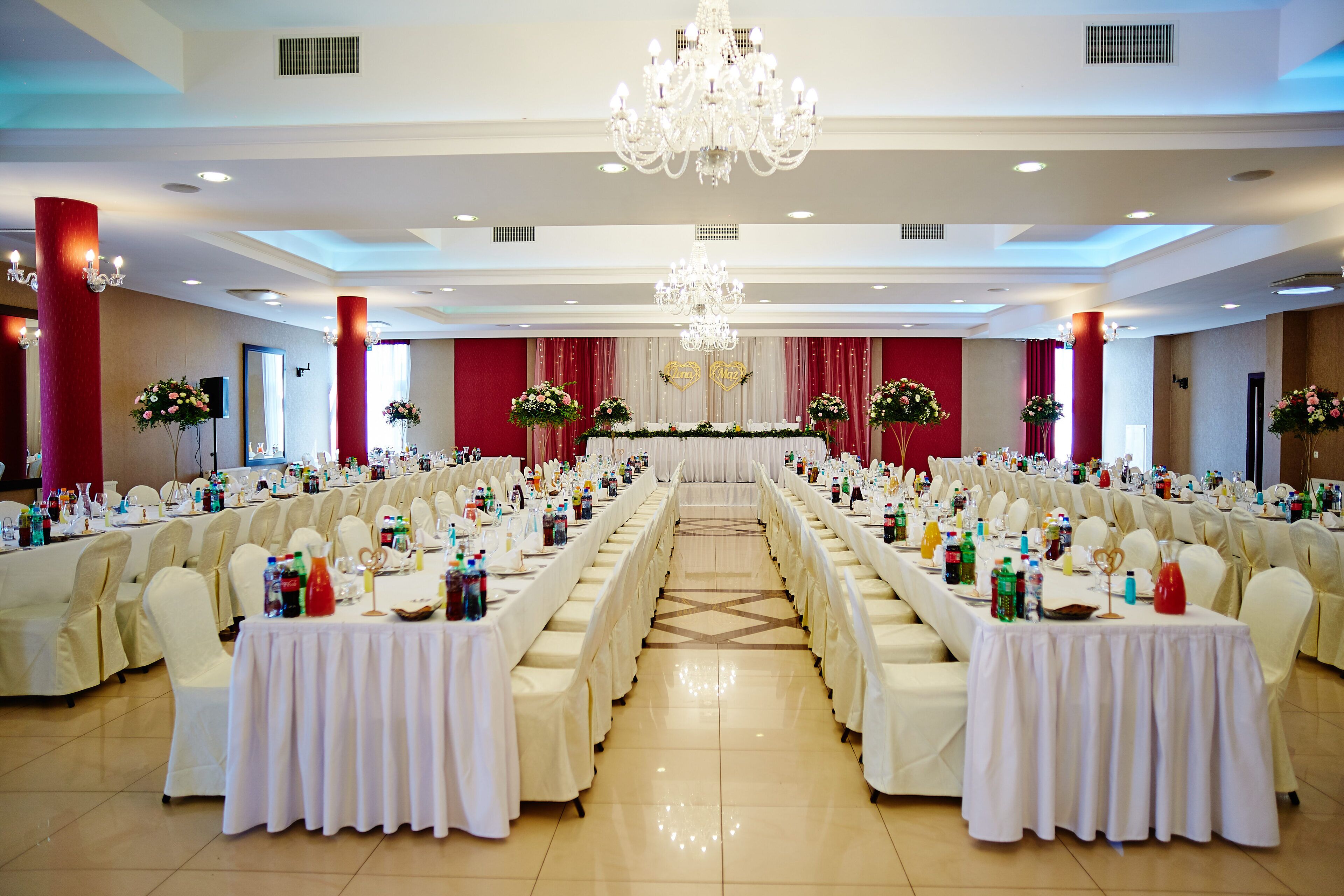 A banquet hall with long tables, white tablecloths, and floral centerpieces.