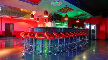 Zona de bar con varios taburetes rojos y una barra.