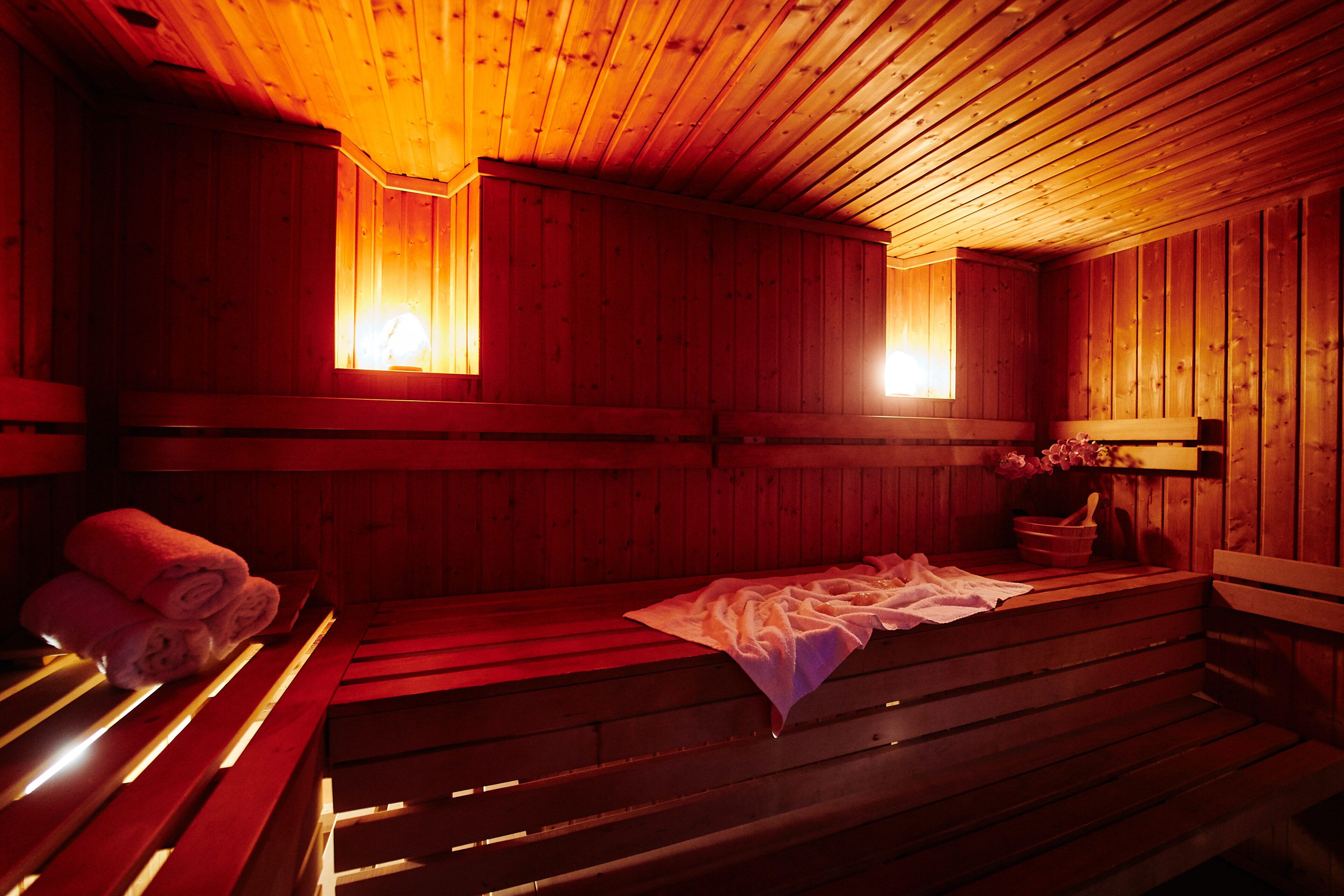 Un sauna con bancos de madera, algunos con toallas y uno con una toalla y un tazón.