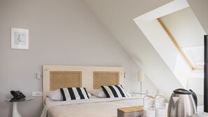 Una habitación de hotel moderna con una cama, una mesita de noche y una pequeña mesa con un hervidor y botellas.