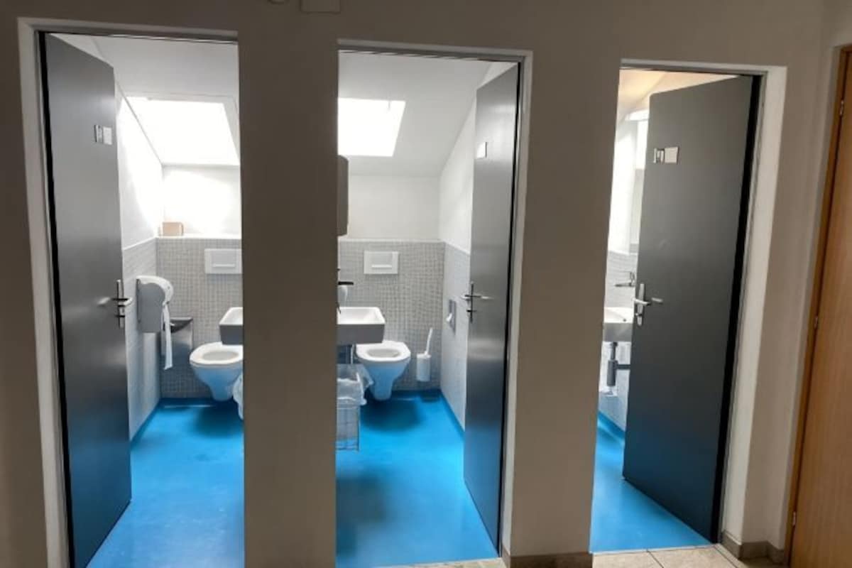 A bathroom with two toilets, a sink, and a mirror.