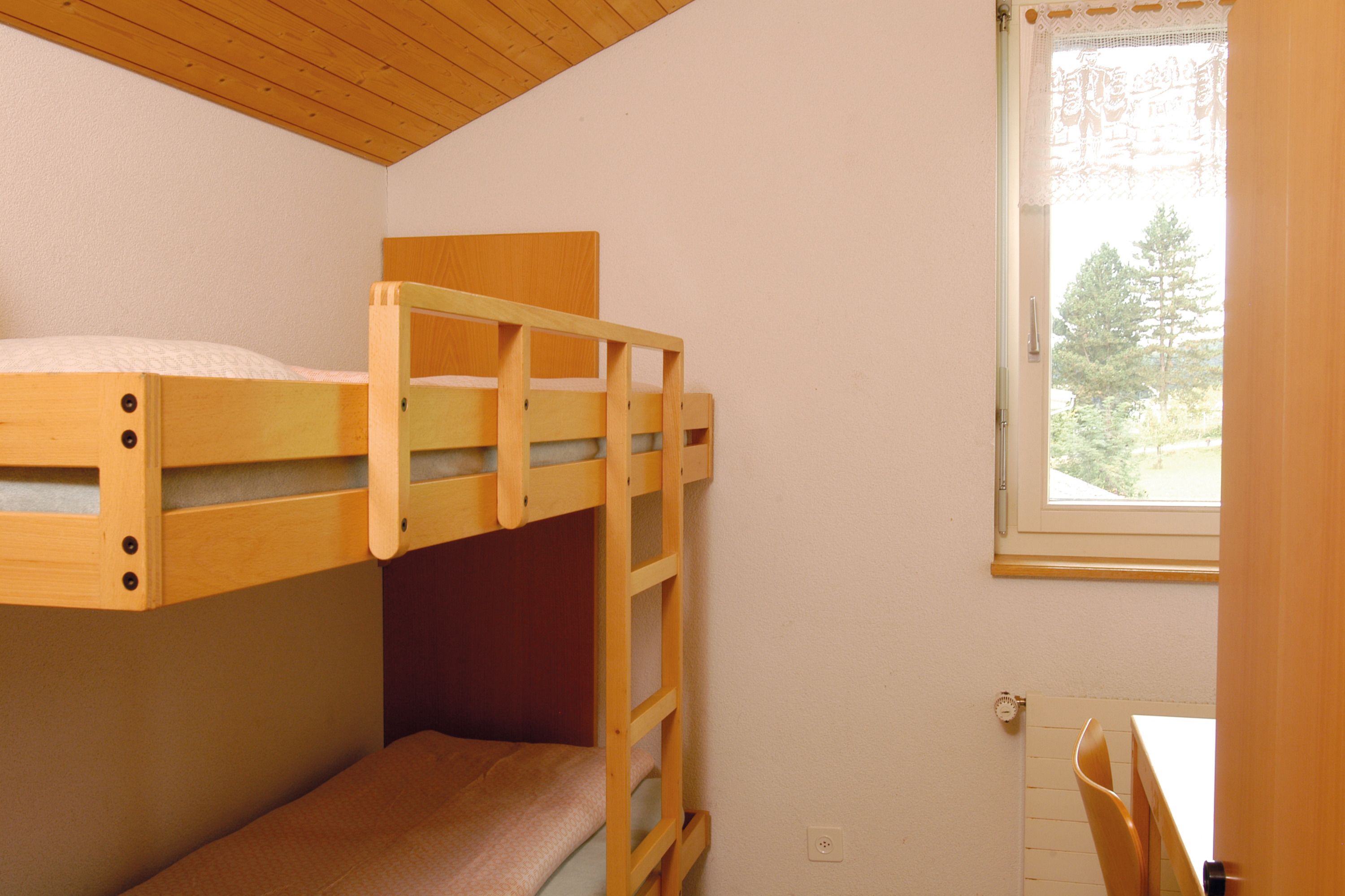 Ein Schlafzimmer mit Etagenbetten, einem Fenster und einem Tisch.
