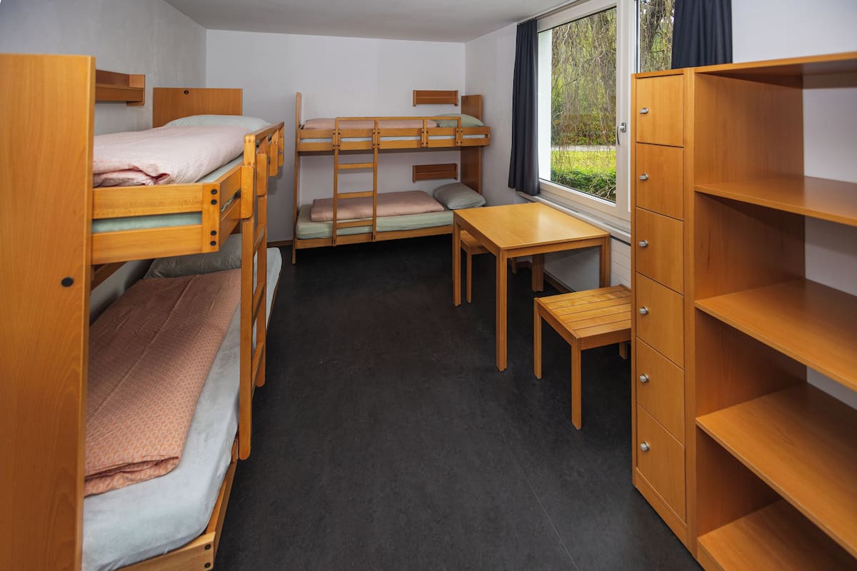 A bunk bed room with a desk and a wardrobe.
