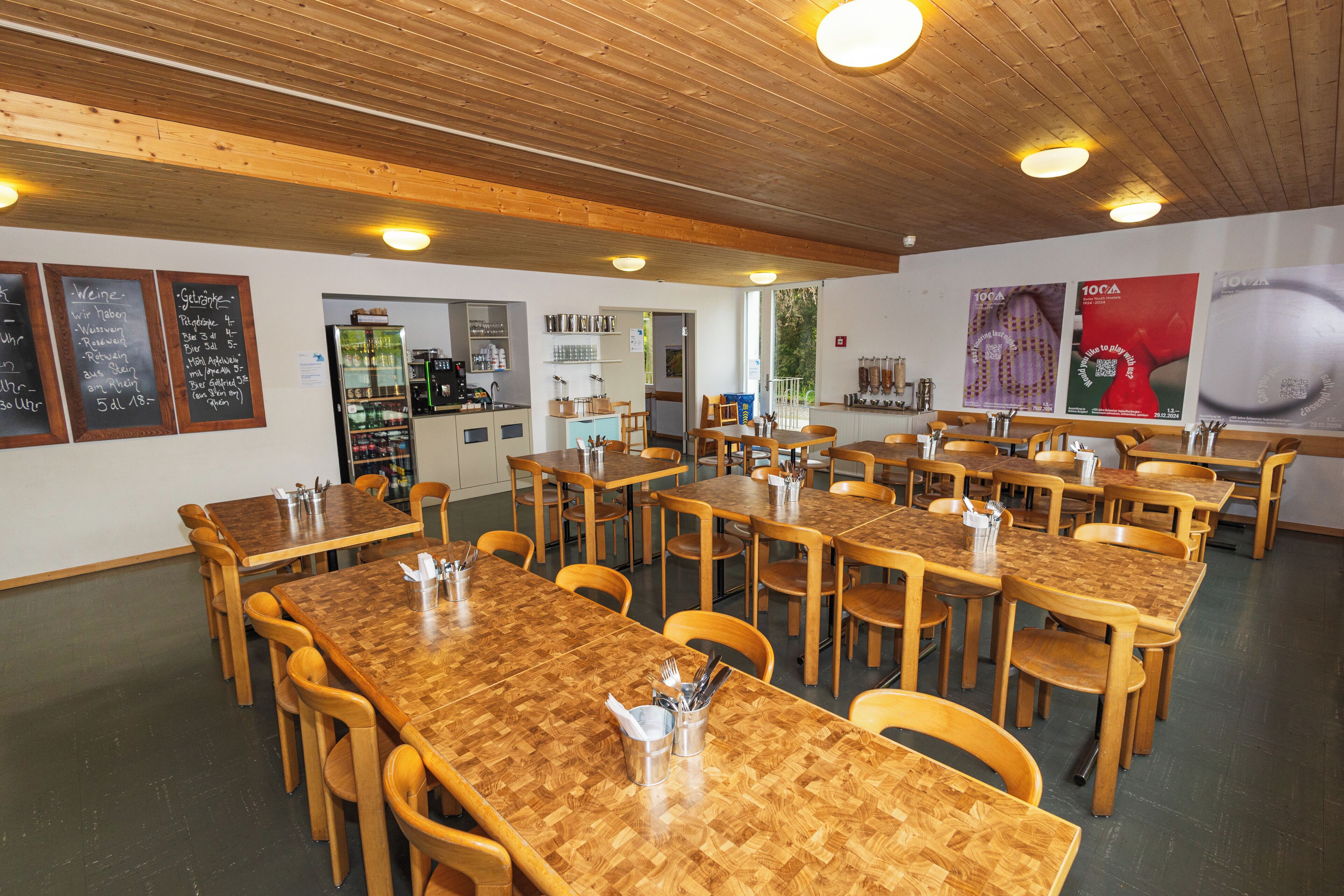 A restaurant with wooden tables and chairs, a bar area, and menu boards on the walls.