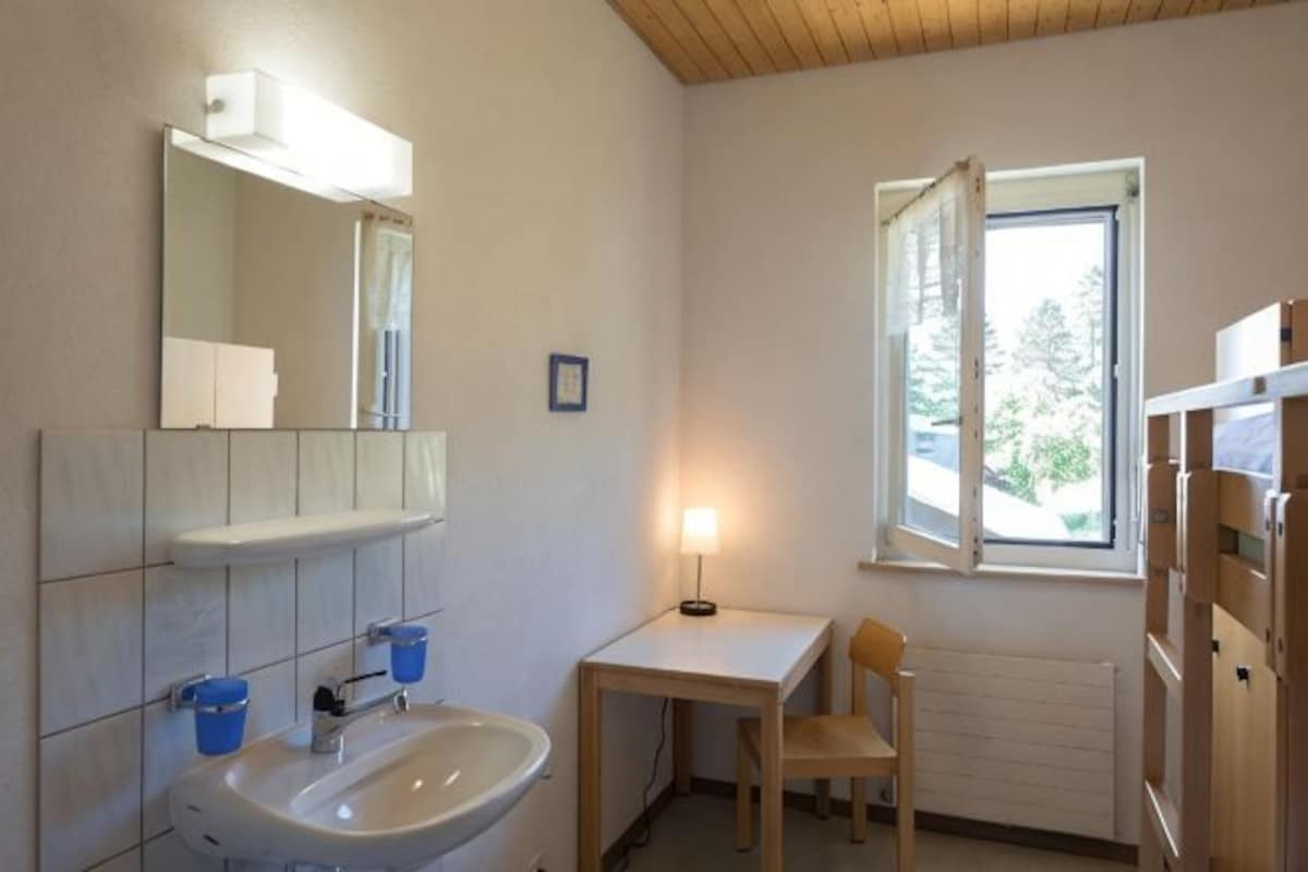 A bathroom with a sink, mirror, and window.