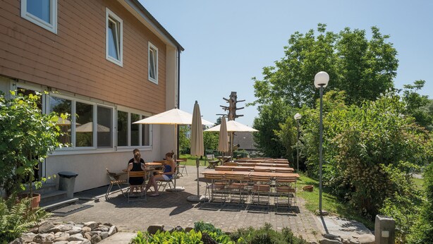 En terrasse med udendørs møbler, en stensætning og et hus i baggrunden.