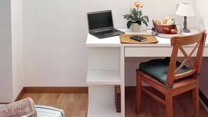 A neatly arranged workspace with a laptop, a potted plant, a lamp, and a chair with a cushion. - MI.style (Milan)