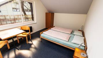 A bedroom with a bed, a desk, and a chair.
