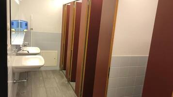 A public restroom with two sinks, a mirror, and a row of stalls.