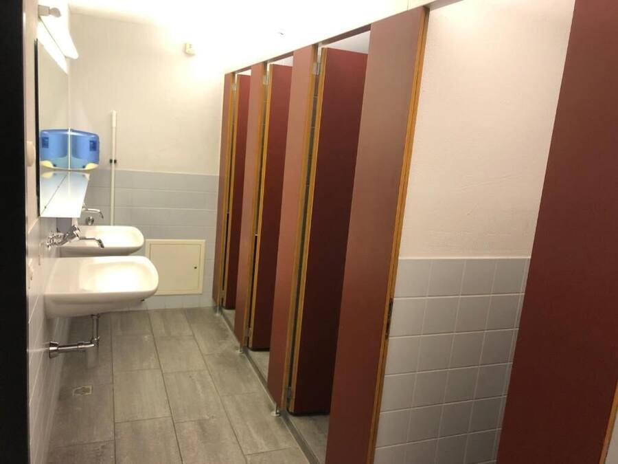 A public restroom with two sinks, a mirror, and a row of stalls.
