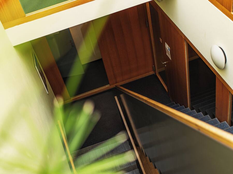 A staircase with wooden steps and a handrail, leading to a landing with a door.
