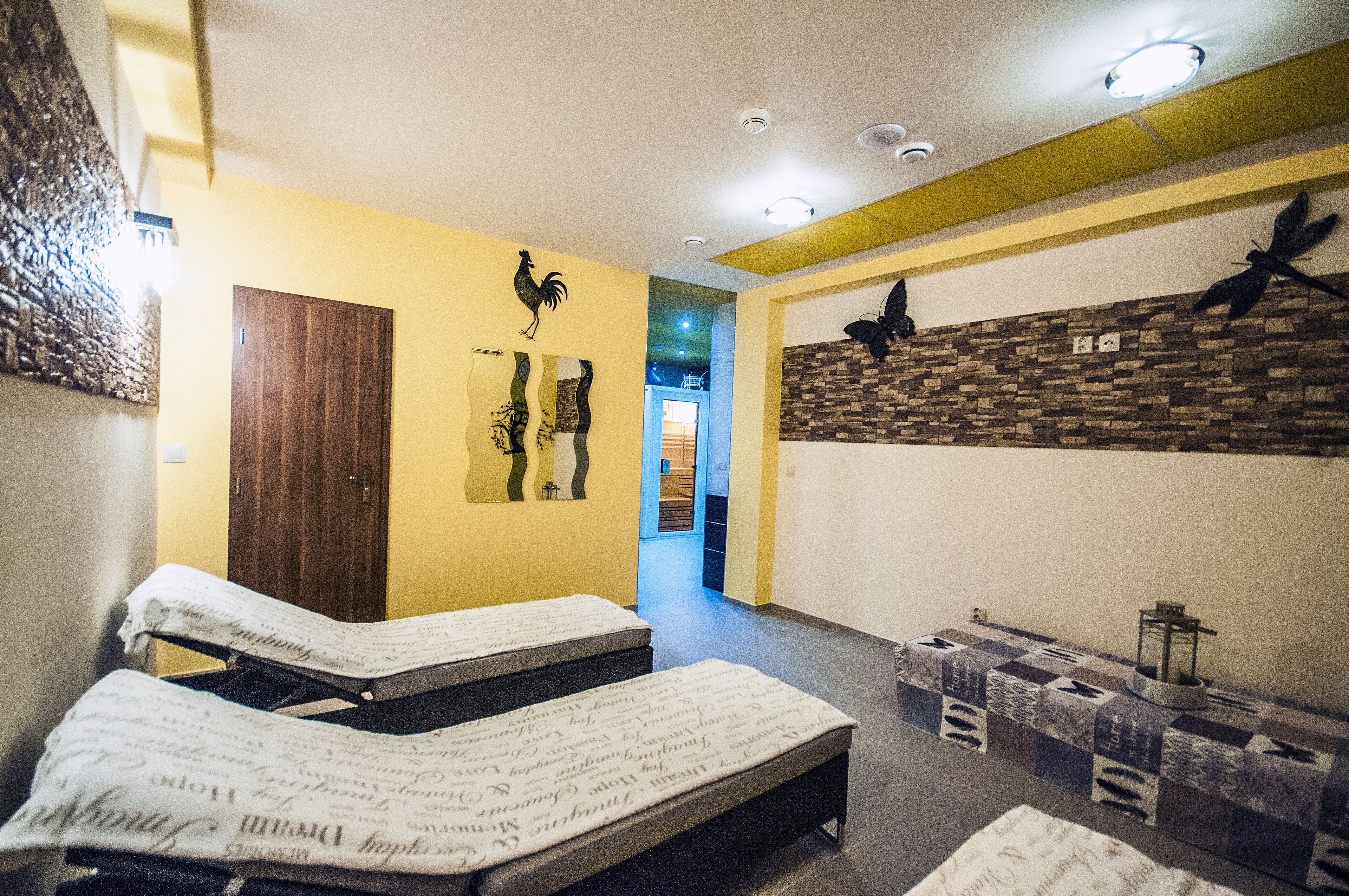 A hotel room with two beds, a wooden door, and a stone wall with wall art.